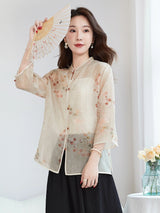 Model wearing a beige silk Cheongsam-style top with a stand collar, holding a folding fan over her face, showcasing the elegance and cultural charm of the design.