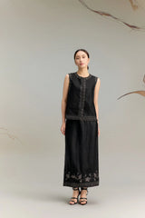 Full body shot of a black silk sleeveless vest top with delicate embroidery along the neckline and hem, featuring a relaxed fit and button-down front.