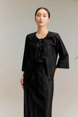 Full body shot of a black silk co-ord set featuring a three-quarter sleeve top with lace trim and tie-front detail, paired with a matching A-line skirt with lace hem, crafted from 100% mulberry silk.