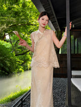 Full body shot of a champagne gold sleeveless vest and midi skirt set with bead embroidery and lace details, holding a folded fan.