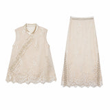 Flat lay of a champagne gold two-piece set featuring a sleeveless embroidered vest with scalloped hem and a matching midi skirt with lace trim.
