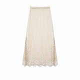 Flat lay of a champagne gold midi skirt with bead embroidery, lace side panels, and a scalloped hem, featuring an elastic waistband.
