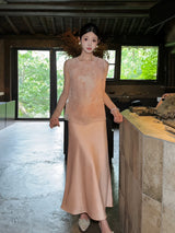 Model wearing a champagne satin maxi skirt paired with an embroidered Cheongsam vest, standing indoors, showcasing the elegant drape of the 100% polyester fabric.