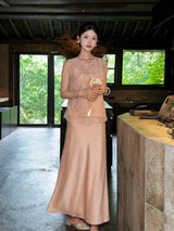 Model standing outdoors in a champagne satin maxi skirt, holding a pink handbag, crafted from 100% polyester, showcasing the versatility of the skirt.
