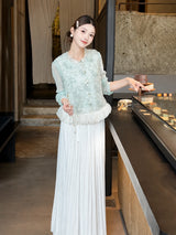 Side view of a cream white shiny pleated maxi skirt styled with a mint green top, highlighting the elegant movement and texture of the pleats.