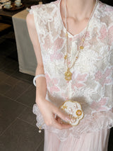 Close-up of a white sheer vest featuring intricate pink floral embroidery, sequins, and pearl buttons, crafted from 100% polyester.
