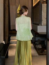 Back view of a green embroidered sleeveless vest with scalloped lace hem, paired with a pleated skirt, highlighting the elegant embroidery details.