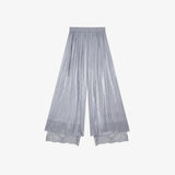 Flat lay of grey pleated wide-leg pants with an elastic waistband, side tie, and layered lace hem, crafted from 100% polyester.