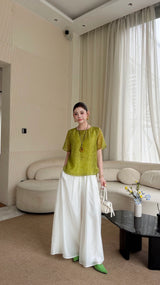 Full body shot of a green short sleeve shirt with a relaxed silhouette, paired with white wide-leg pants and a white handbag.