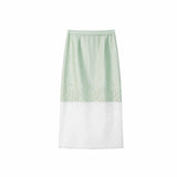 Flat lay of a mint green midi skirt with floral embroidery and a sheer white hem panel, crafted from a Lyocell-polyester blend.