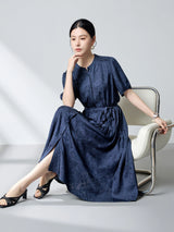 Sitting model in a navy blue silk dress with a tiered skirt and side slits, highlighting the elegant drape and flattering silhouette of the 100% mulberry silk fabric.