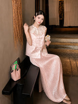 Model sitting in a pink shiny pleated maxi skirt with a matching embroidered vest, holding a fan, crafted from 100% polyester.