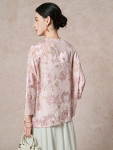 Back view of a sheer pink 100% silk blouse featuring delicate cutwork floral embroidery and a round neckline, paired with a pleated skirt.