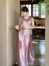 Side view of a purple shiny pleated skirt styled with a textured top, adjusting the side tie detail, crafted from 100% polyester.