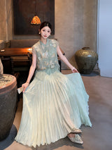 Sitting model in a sage green pleated skirt with a matching embroidered top, highlighting the elegant pleats and comfortable fit.