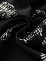 Close-up of the 100% silk crepe fabric showing the crisp white abstract floral print on a black background, highlighting the texture and sheen.