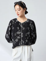 Side profile of a black printed silk blouse showcasing the flowy silhouette and three-quarter puff sleeves, crafted from 100% mulberry silk.