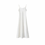 Flat lay of a white satin slip dress with silver-toned strap hardware and a minimalist design, crafted from 100% polyester.
