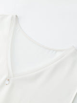 Close-up of the V-neckline on a white silk blend vest, showcasing the fine stitching, delicate edge, and the 100% mulberry silk trim detail.